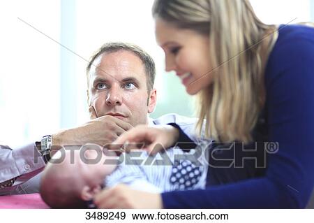 Stock Photo - France, mother looking at baby, father dreaming. Fotosearch