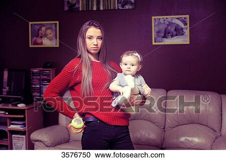 Stock Image - France, nanny or very new mother in the living room. Fotosearch