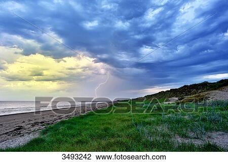 Stock Image - France, Normandy. Annoville. The dunes and the beach. Thunderstorm and lightning falling on the tip of Agon-Coutainville.. Fotosearch