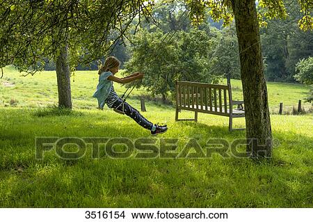 France, Normandy, little girl enjoying a go on a swing in a beautiful countryside garden View Large Photo Image Picture - France, Normandy, little girl enjoying a go on a swing in a beautiful countryside garden. Fotosearch