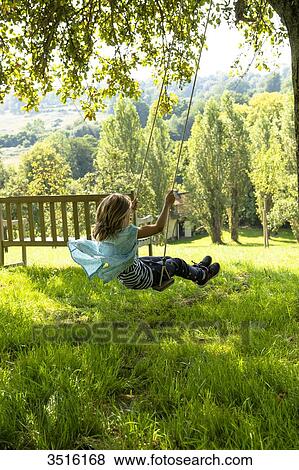 France, Normandy, little girl enjoying a go on a swing in a beautiful countryside garden View Large Photo Image Stock Photo - France, Normandy, little girl enjoying a go on a swing in a beautiful countryside garden. Fotosearch