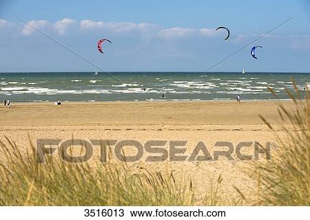 Stock Image - France, Normandy, people enjoying a windy afternoon at the seaside, kite surfing. Fotosearch