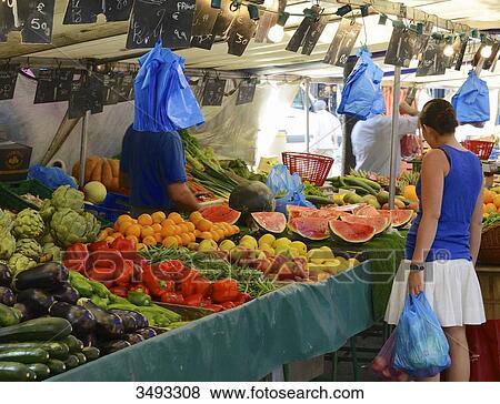 Stock Photo - France, Paris, 15th arrondissement, Saint Charles market. Woman from behind, in front of a fruit and vegetables stand.. Fotosearch