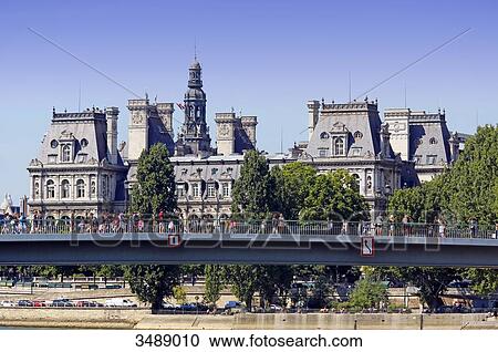 Stock Image - France, Paris, 4th arrondissement, facade of the Hotel de Ville (Seine side). In the foreground: the Saint Louis bridge, tourists on it. Fotosearch