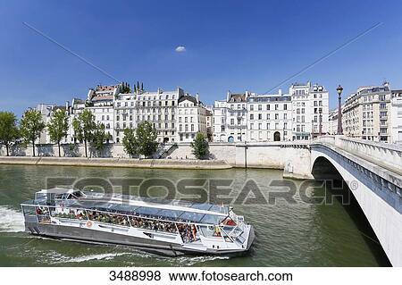 Stock Photo - France, Paris. 4th arrondissement. The Ile Saint Louis. Boat on the Seine. Tournelle Bridge in the foreground on the right.. Fotosearch