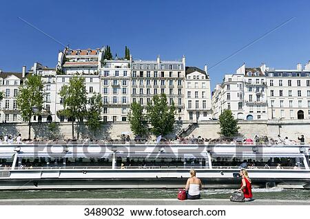 France, Paris. 5th arrondissement. Tourists looking at a passing boat. In the background the Ile Saint Louis. View Large Photo Image Stock Image - France, Paris. 5th arrondissement. Tourists looking at a passing boat. In the background the Ile Saint Louis.. Fotosearch