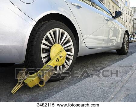 Stock Photography - France, Paris. 8th district. Wheel clamp impeding parked car on a bus/taxis lane. Fotosearch