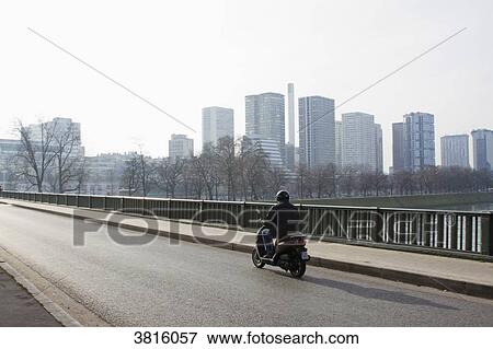 Stock Photo - France, Paris, Bir-Hakeim on Sunday morning, a man riding a scooter in winter.. Fotosearch