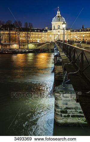 Stock Photo - France, Paris, Pont des Arts and Mazarine library at nighttime. Fotosearch