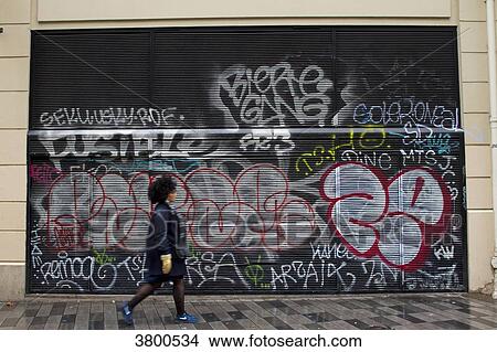 France, Paris, woman walking in front of an iron curtain covered witn graffiti. View Large Photo Image Picture - France, Paris, woman walking in front of an iron curtain covered witn graffiti.. Fotosearch