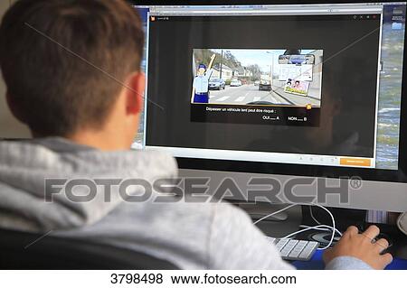 Stock Photo - France, teenager being exerted with the highway code by Internet.. Fotosearch