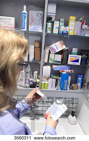 Stock Image - France, woman in front of medicine cabinet. Fotosearch