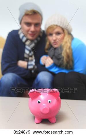 Stock Photo - France, young couple dressed warmly, piggybank. Fotosearch