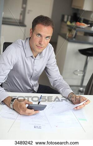 Stock Image - France, young man studying his invoices. Fotosearch