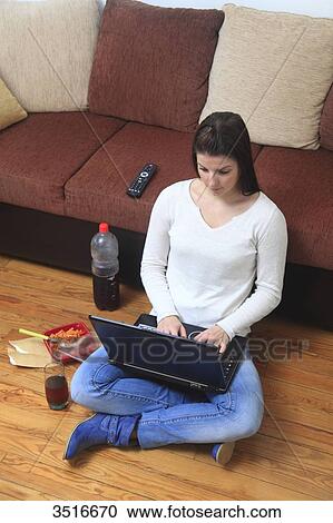 Stock Image - France, young woman at home, eating and working. Fotosearch