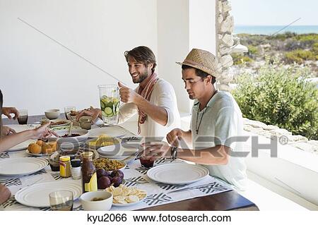 Friends eating lunch at dining table View Large Photo Image Stock Photograph - Friends eating lunch at dining table. Fotosearch