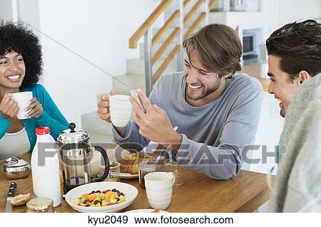 Friends enjoying at a dining table View Large Photo Image Stock Photo - Friends enjoying at a dining table. Fotosearch