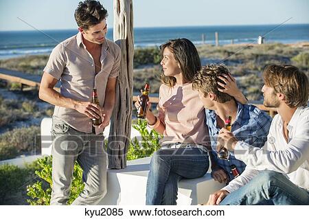 Stock Photography - Group of friends enjoying beer outdoors on vacation. Fotosearch