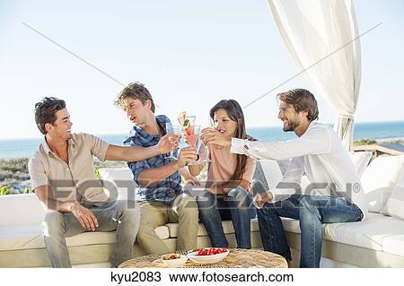 Stock Image - Group of friends toasting drinks outdoors on vacation. Fotosearch