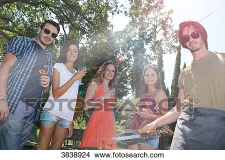 Groupe of happy and cheerful young people having fun around barbecue grill during summer holiday party outdoor in the garden. View Large Photo Image Picture - Groupe of happy and cheerful young people having fun around barbecue grill during summer holiday party outdoor in the garden.. Fotosearch