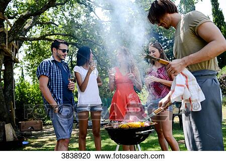 Groupe of happy and cheerful young people having fun around barbecue grill during summer holiday party outdoor in the garden. View Large Photo Image Stock Image - Groupe of happy and cheerful young people having fun around barbecue grill during summer holiday party outdoor in the garden.. Fotosearch