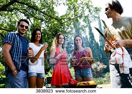 Groupe of happy and cheerful young people having fun around barbecue grill during summer holiday party outdoor in the garden. View Large Photo Image Stock Image - Groupe of happy and cheerful young people having fun around barbecue grill during summer holiday party outdoor in the garden.. Fotosearch