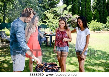 Groupe of happy and cheerful young people having fun around barbecue grill during summer holiday party outdoor in the garden. View Large Photo Image Stock Image - Groupe of happy and cheerful young people having fun around barbecue grill during summer holiday party outdoor in the garden.. Fotosearch