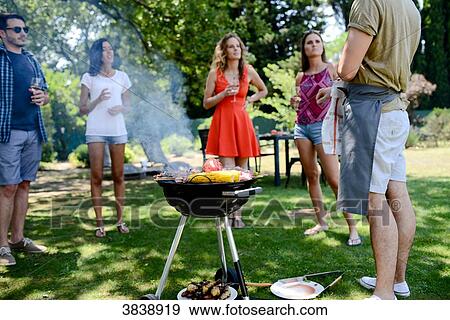 Groupe of happy and cheerful young people having fun around barbecue grill during summer holiday party outdoor in the garden. View Large Photo Image Stock Photo - Groupe of happy and cheerful young people having fun around barbecue grill during summer holiday party outdoor in the garden.. Fotosearch