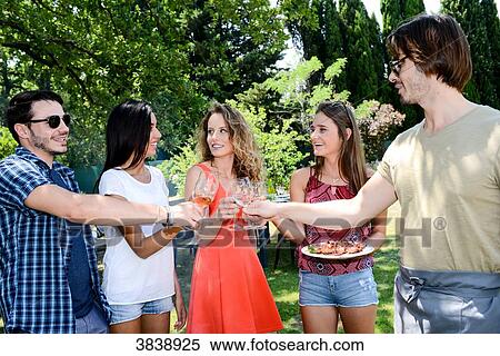 Groupe of happy and cheerful young people having a toast around barbecue grill during summer holiday party outdoor in the garden. View Large Photo Image Stock Photography - Groupe of happy and cheerful young people having a toast around barbecue grill during summer holiday party outdoor in the garden.. Fotosearch
