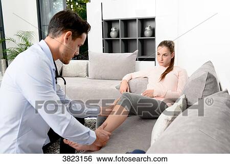 Stock Photograph - handsome young doctor visiting a woman patient at home. Fotosearch