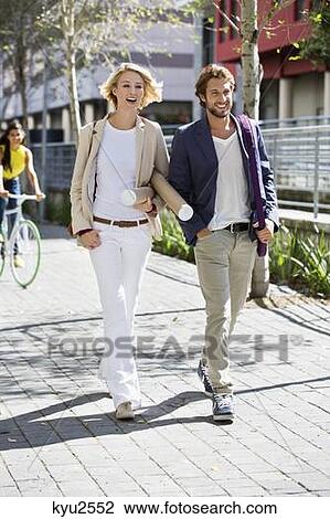 Stock Image - Happy couple walking on a street. Fotosearch