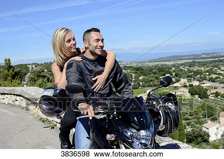 Stock Photo - Happy young biker couple riding motorbike in summer.. Fotosearch