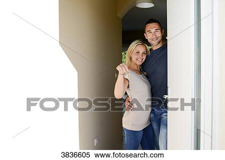 Happy young couple at the front door of new house showing proudly their home key. View Large Photo Image Stock Photography - Happy young couple at the front door of new house showing proudly their home key.. Fotosearch