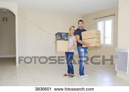 Happy young couple carrying cardboard boxes and moving into their new house. View Large Photo Image Stock Image - Happy young couple carrying cardboard boxes and moving into their new house.. Fotosearch