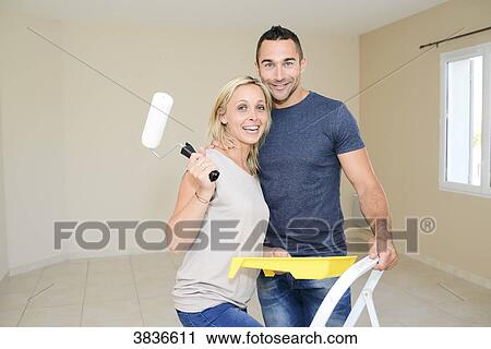Stock Image - Happy young couple renovating painting and moving into their new house.. Fotosearch