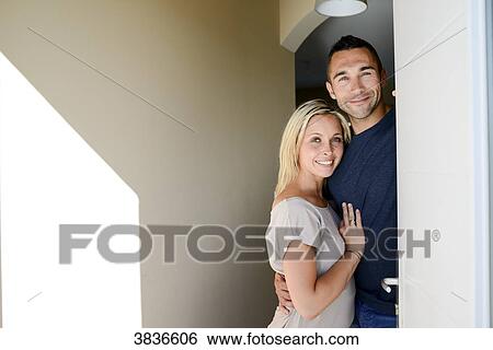 Happy young couple welcoming friends at the front door of new house. View Large Photo Image Stock Photograph - Happy young couple welcoming friends at the front door of new house.. Fotosearch