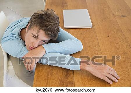 Stock Image - High angle view of a man leaning on a table with a laptop. Fotosearch