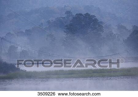 Stock Photograph - India, Chhattisgarh, Kawardha district, Bhoramdeao, Suspensio bridge in the mist. Fotosearch