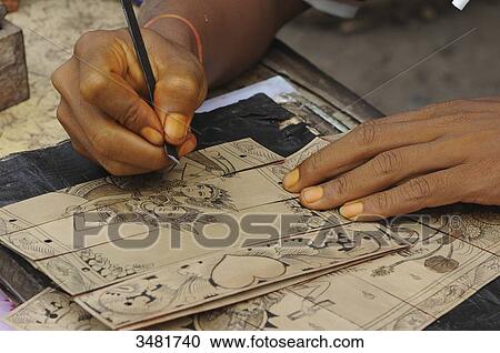 Stock Image - Indonesia, Bali, animist village of Tenganan. Here an ornamentist craftsman making a masterpiece of Rmyana (short story of mythological epic) on dried palm leaves.. Fotosearch