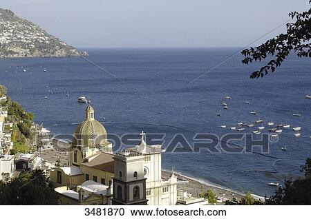 Stock Image - Italy, Amalfi Coast, Positano, panorama of the old fishermen village with the Santa Maria Assunta church and its dome covered in varnished tiles, near the beach. Fotosearch