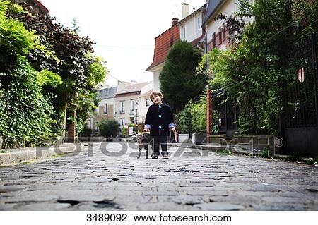 Stock Image - Little boy and a cat in a cobbled narrow street. Fotosearch