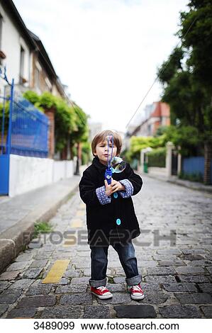 Little boy blowing bubbles in the street View Large Photo Image Stock Photo - Little boy blowing bubbles in the street. Fotosearch