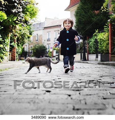 Stock Image - Little boy running in a cobbled narrow street. Fotosearch