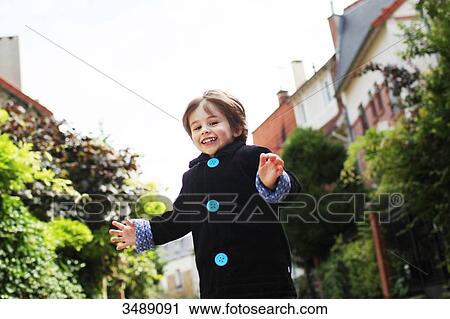 Stock Image - Little boy running in a cobbled narrow street. Fotosearch