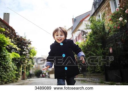 Stock Photo - Little boy running in a cobbled narrow street. Fotosearch