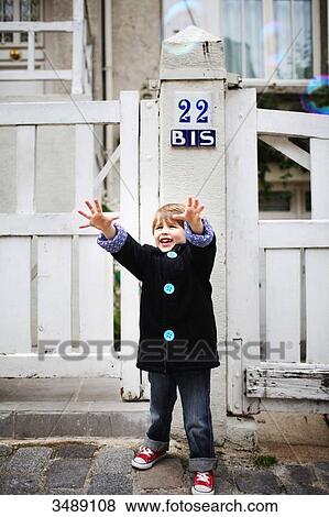 Little boy with outstretched arms trying to catch bubbles in the street View Large Photo Image Stock Photo - Little boy with outstretched arms trying to catch bubbles in the street. Fotosearch