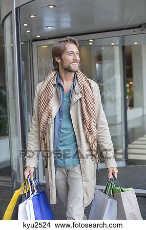 Picture - Man carrying shopping bags and smiling. Fotosearch