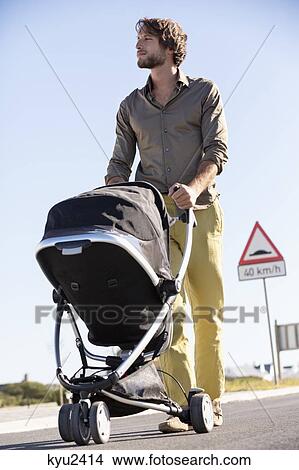 Picture - Man pushing a baby stroller. Fotosearch