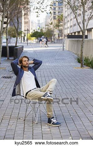 Stock Photography - Man relaxing on a chair on a street. Fotosearch