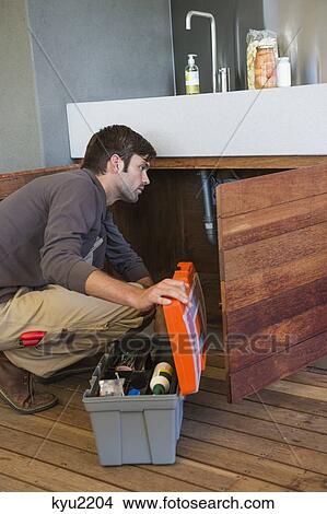 Picture - Man repairing a kitchen sink. Fotosearch